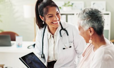 Mature woman, doctor and tablet for healthcare, support or conversation with checkup appointment in office. Female person, medical professional and diagnosis talk for senior patient at clinic