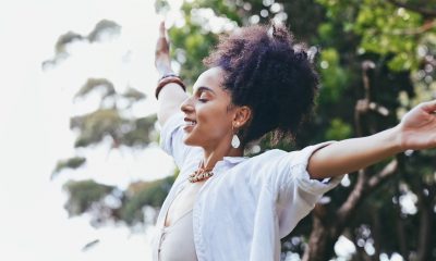 Zen, freedom and black woman with open arms, nature and peace with smile, balance and joyful outdoor. African American female, lady or meditation for fresh air, carefree or celebration with happiness