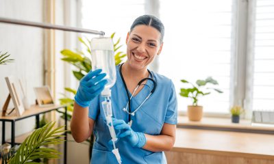 Portrait of a home care nurse adjusting and preparing an IV drip inside an apartment,